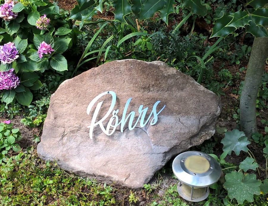 Namensschild Röhrs als Metall-Schriftzug auf einem Findling im Garten